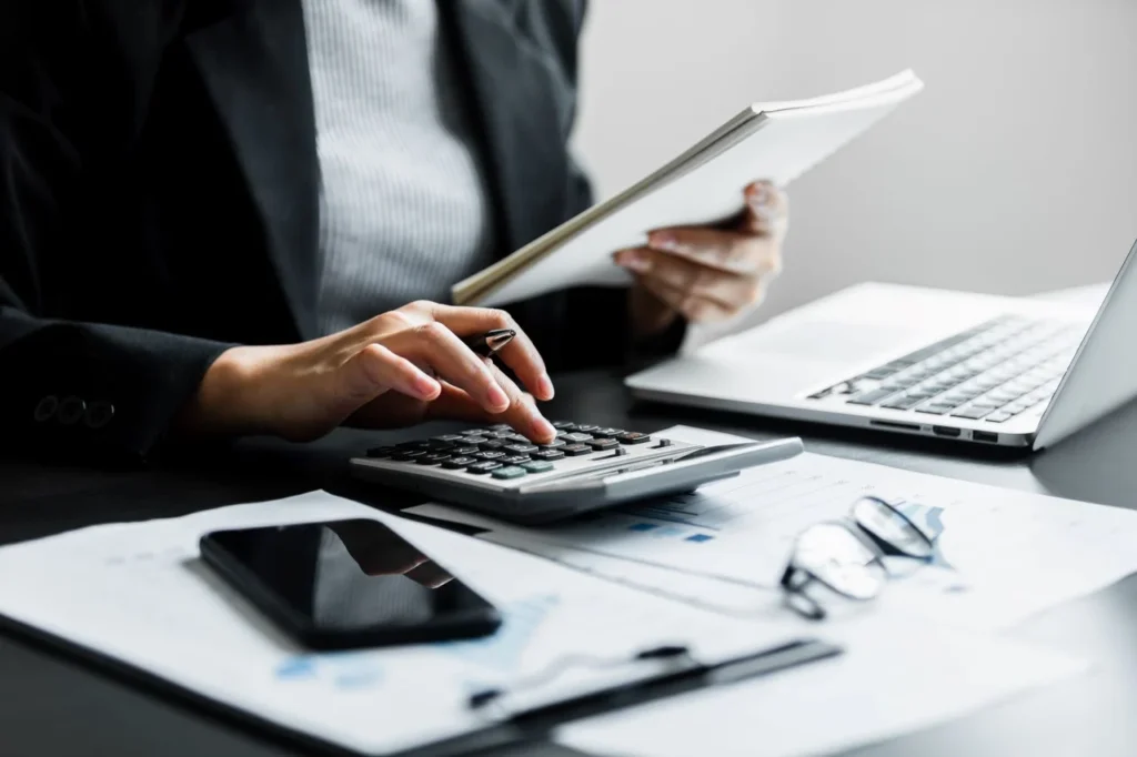Accountant reviewing financial documents with a calculator and laptop